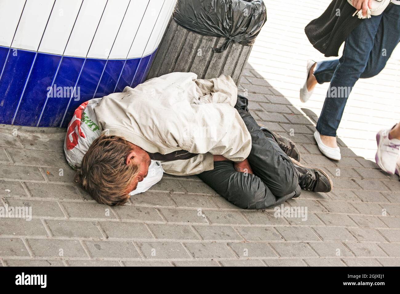Dnepropetrovsk, UKRAINE - 09.05.2021: Un mendiant sans-abri dort dans la rue. Les sans-abri, les gens sales dorment dans les rues pavées. Problème social. Begga Banque D'Images