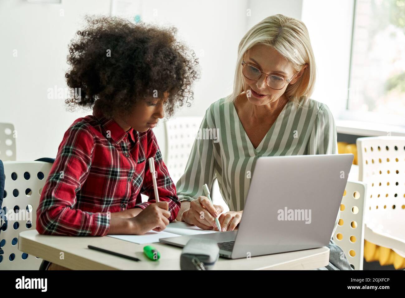 Afro-américaine écolière apprenant avec une enseignante enseignante enseignante utilisant un ordinateur portable. Banque D'Images