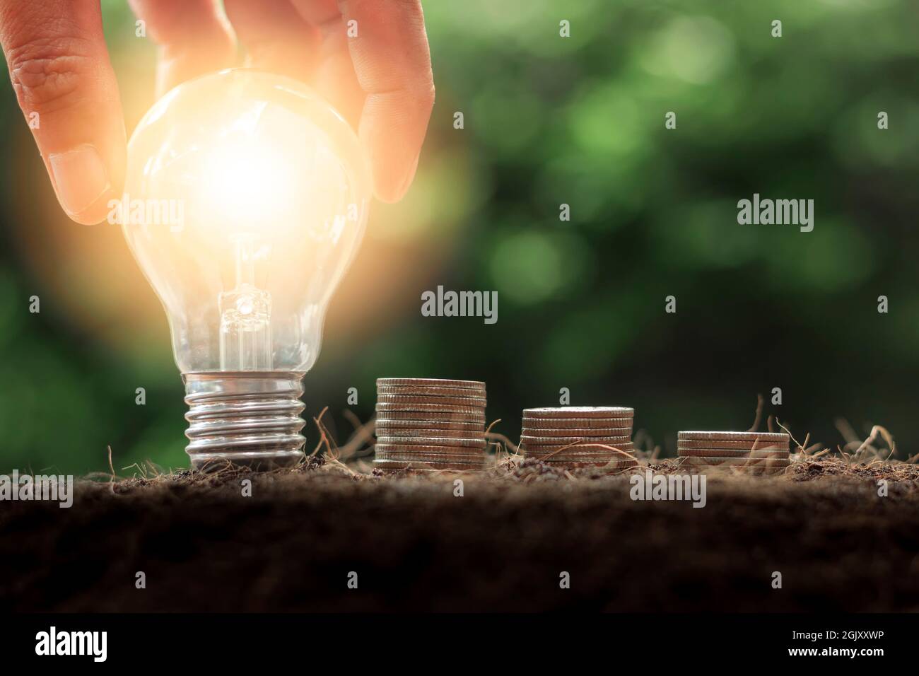Ampoule à main avec pile de pièces. Succès commercial, économies, gestion de l'argent pour le futur concept, Banque D'Images