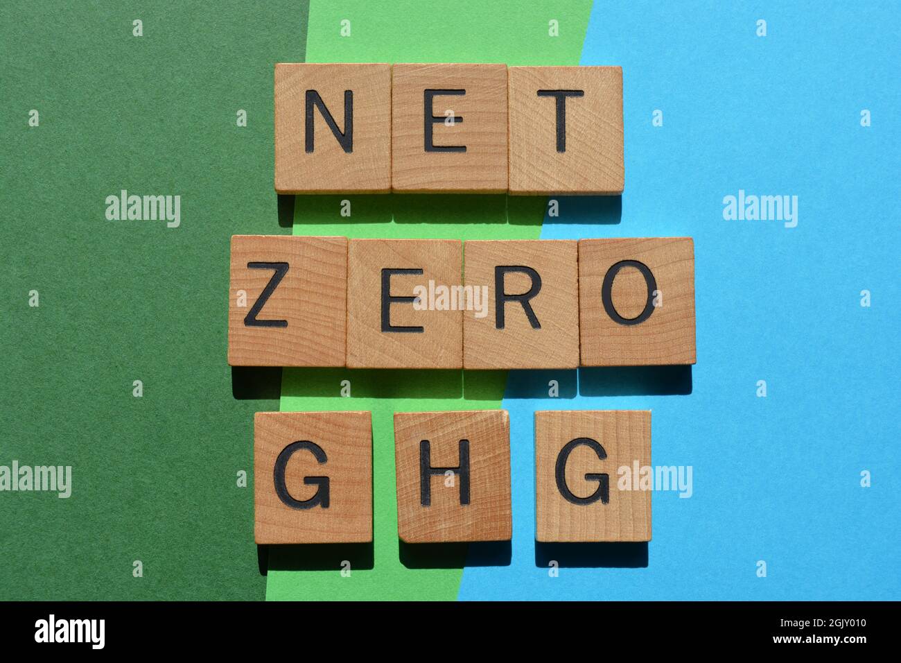 Net Zero GHG, mots en lettres de l'alphabet en bois isolés sur fond bleu et vert Banque D'Images