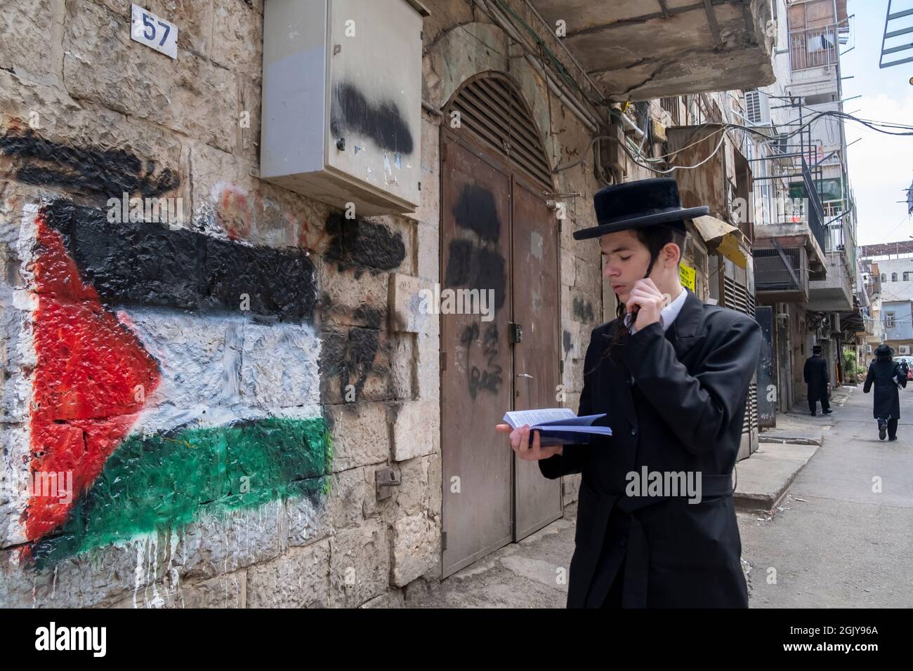 Un juif orthodoxe marche à côté d'un drapeau palestinien peint par pulvérisation sur un mur par des juifs haredi antisionistes extrêmes dans le quartier de MEA Shearim, une enclave ultra-orthodoxe dans Jérusalem-Ouest Israël Banque D'Images