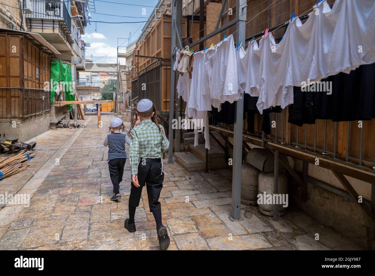 Les enfants juifs orthodoxes marchent dans une rue pleine de huttes traditionnelles temporaires en bois de 'Sukkot' construites pour être utilisées pendant la semaine du festival juif de Sukkot ou de Sukkoth dans le quartier juif de Batei Ungarin Haredi près de l'enclave ultra-orthodoxe de MEA Shearim dans l'ouest de Jérusalem Israël Banque D'Images