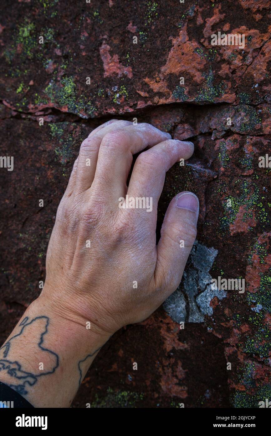 Gros plan de la main crayeuse d'un grimpeur qui saisit une petite prise sur un rocher. Banque D'Images