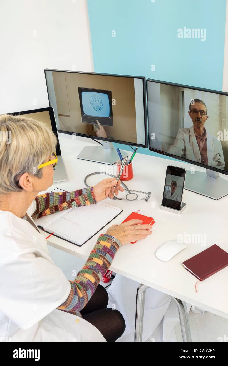 Téléconsultation entre deux médecins avec une cellule souche sur l'un des écrans. Banque D'Images