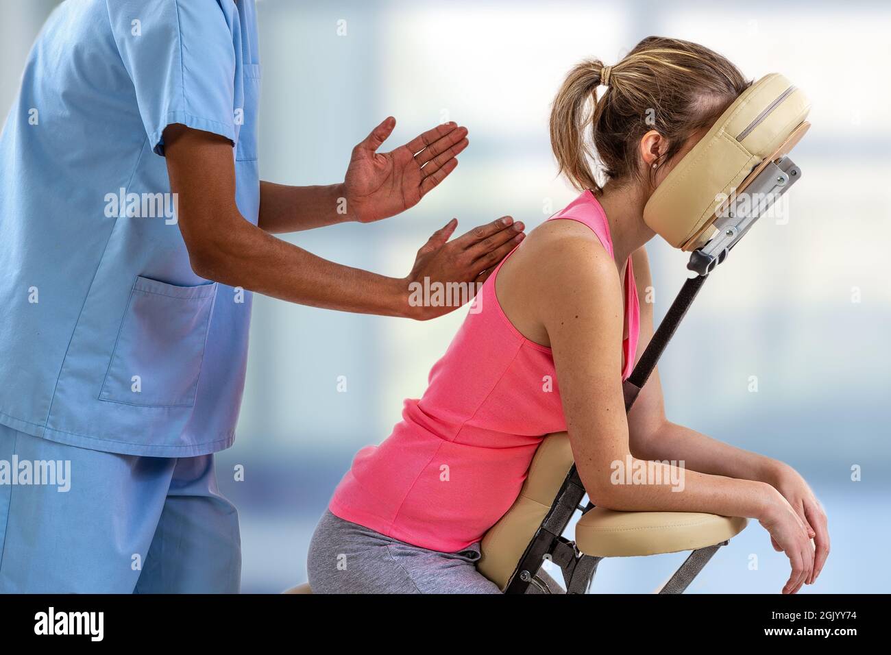 Physiothérapeute donnant un massage de dos à un patient assis dans une chaise de massage dans la clinique Banque D'Images