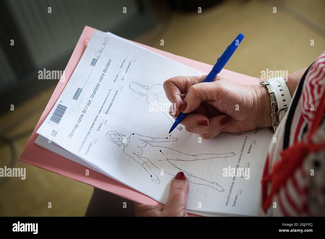 Un patient remplit un formulaire pour évaluer et cibler la douleur chronique. Banque D'Images