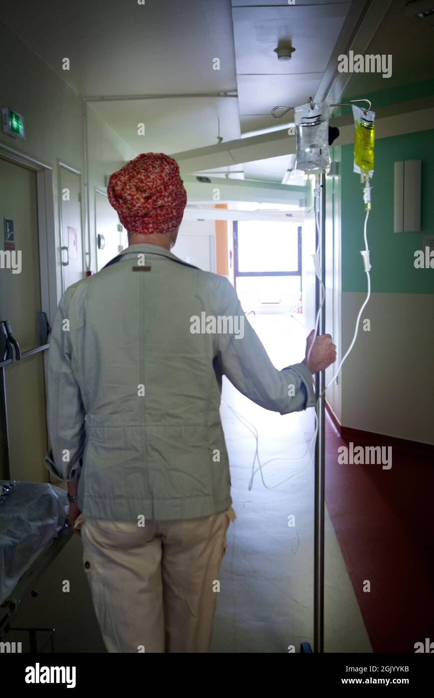 Patient dans un couloir d'hôpital se déplaçant avec son écoulement de chimiothérapie. Banque D'Images