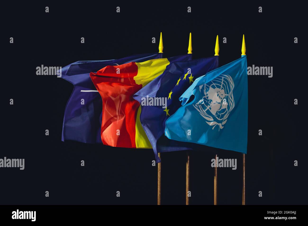 Otopeni, Roumanie - 9 septembre 2021 : les drapeaux de l'OTAN, de la Roumanie, de l'Union européenne et des Nations Unies dans le vent la nuit. Banque D'Images