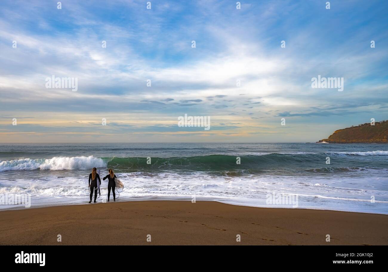 les filles sur la côte attendent pour apprendre le surf Banque D'Images