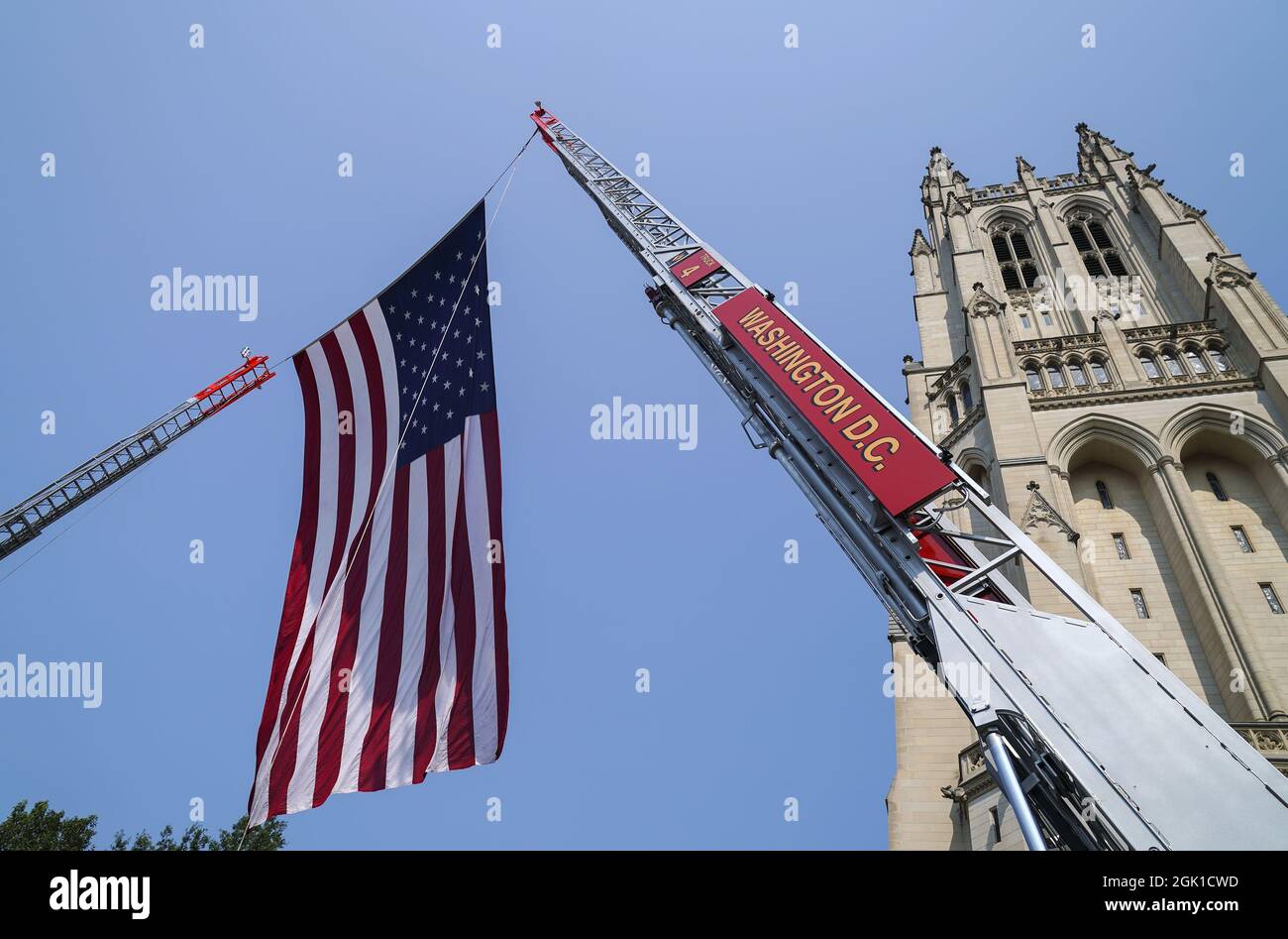 Washington, États-Unis. 12 septembre 2021. Un drapeau américain est suspendu entre deux pompiers de D.C. garés en l'honneur des pompiers qui ont perdu la vie le 11 septembre 2001 à la cathédrale nationale de Washington à Washington, DC, le dimanche 12 septembre 2021. Un service commémoratif a été organisé pour le 20e anniversaire des attentats du 11 septembre afin de rendre hommage aux premiers intervenants qui sont morts dans les attentats. Photo de Leigh Vogel/UPI crédit: UPI/Alay Live News Banque D'Images