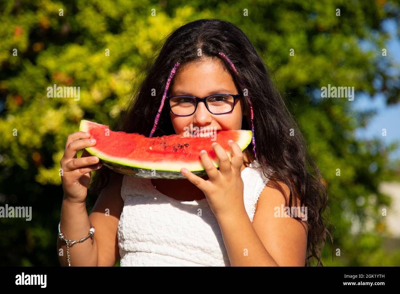 une fille gitane aux cheveux longs noirs mange la grande tranche de pastèque Banque D'Images