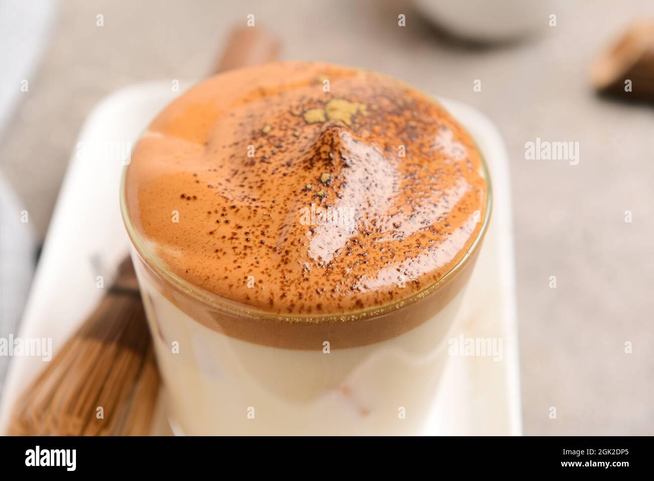 Verre de délicieux dalgona hojicha latte sur fond gris, gros plan Banque D'Images