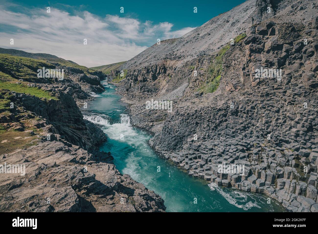 Vue d'ensemble du canyon de Studlagil en Islande, vallée pittoresque avec des colonnes de basalte debout sur une chaude journée d'été. Photo prise dans l'herbe Banque D'Images