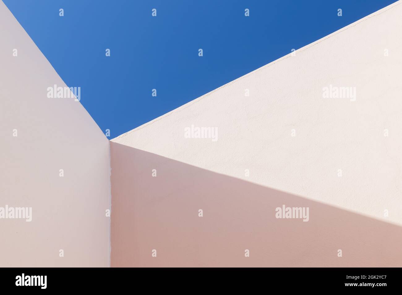 Résumé fragment d'architecture minimal, coin intérieur des murs peints en rose est sous ciel bleu Banque D'Images