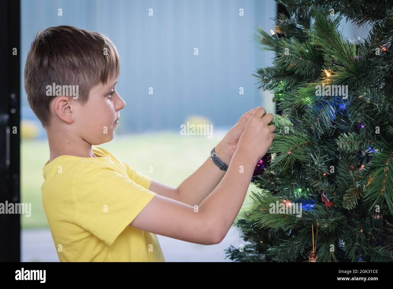 Portrait d'un garçon décorant un arbre de Noël chez lui en Australie méridionale Banque D'Images