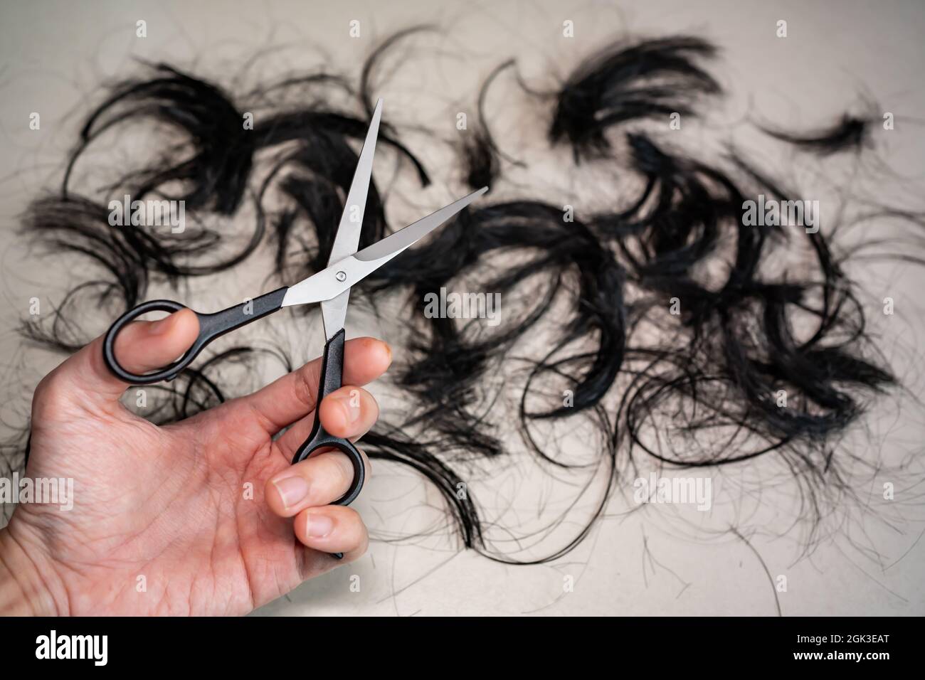 Ciseaux professionnels de coupe de cheveux dans la main gauche avec les cheveux sur le sol Banque D'Images