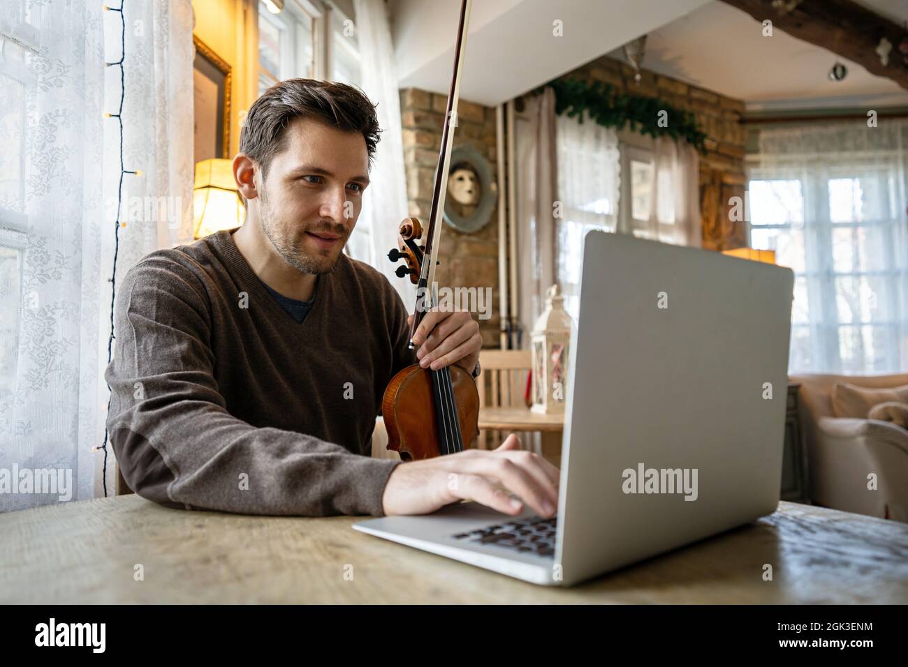 L'étudiant apprend à jouer du violon en ligne à l'aide d'un ordinateur portable. Banque D'Images