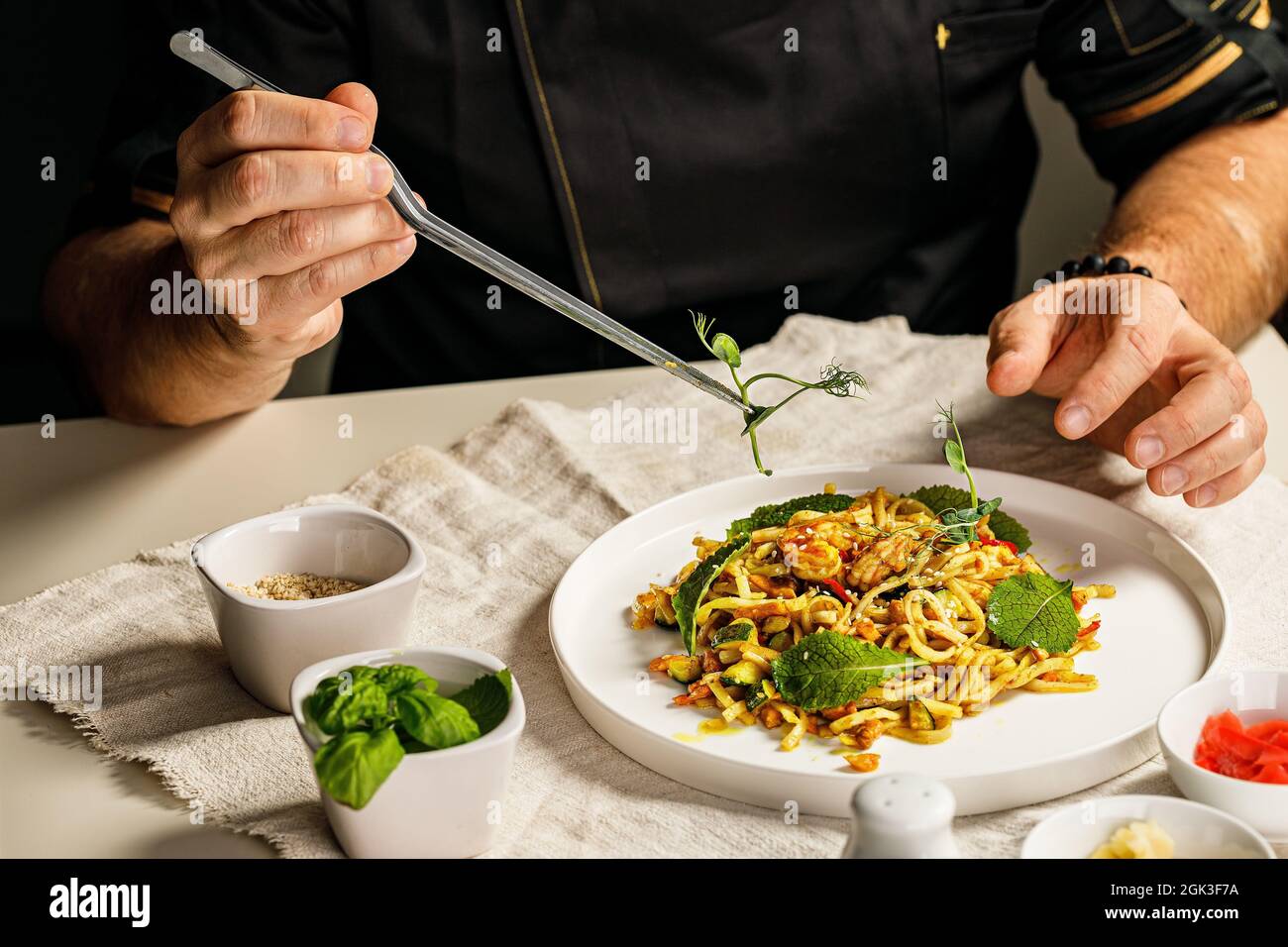 Spaghetti aux fruits de mer. Les mains du chef préparent des pâtes traditionnelles avec des fruits de mer. Le chef décorera le plat avec des herbes à l'aide de pinces. Resta Banque D'Images
