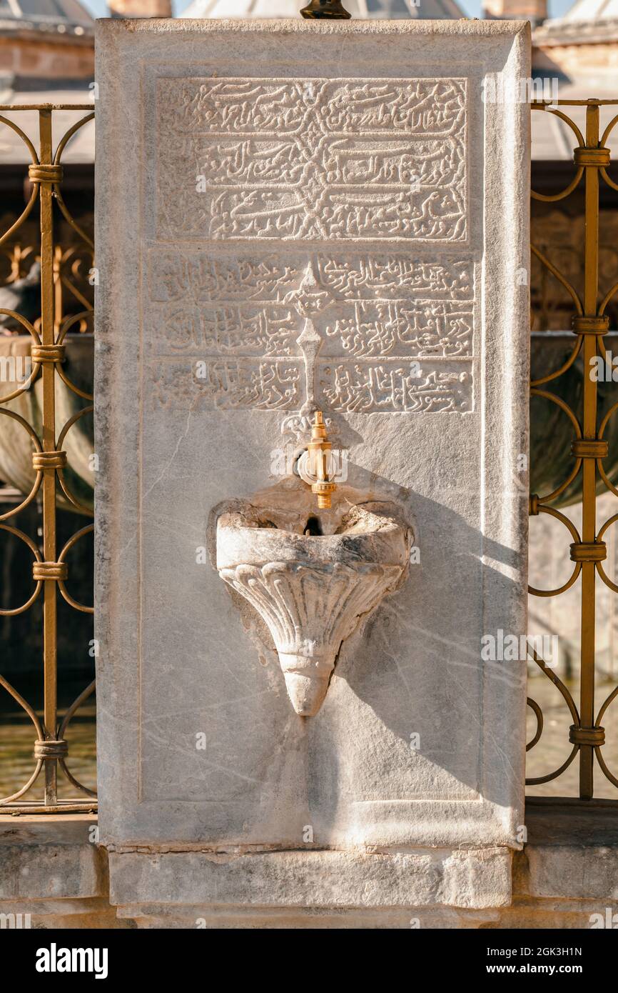 Photo en gros plan d'un robinet sur une grande vieille pierre de marbre avec des écrits arabes gravés dans le mausolée de Mevlana à Konya, Turquie. Banque D'Images