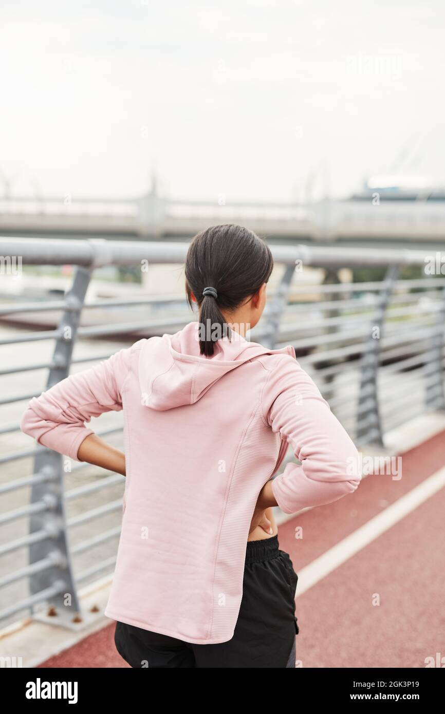 Vue arrière de la jeune femme debout sur le stade de sport et de l'entraînement seul à l'extérieur Banque D'Images