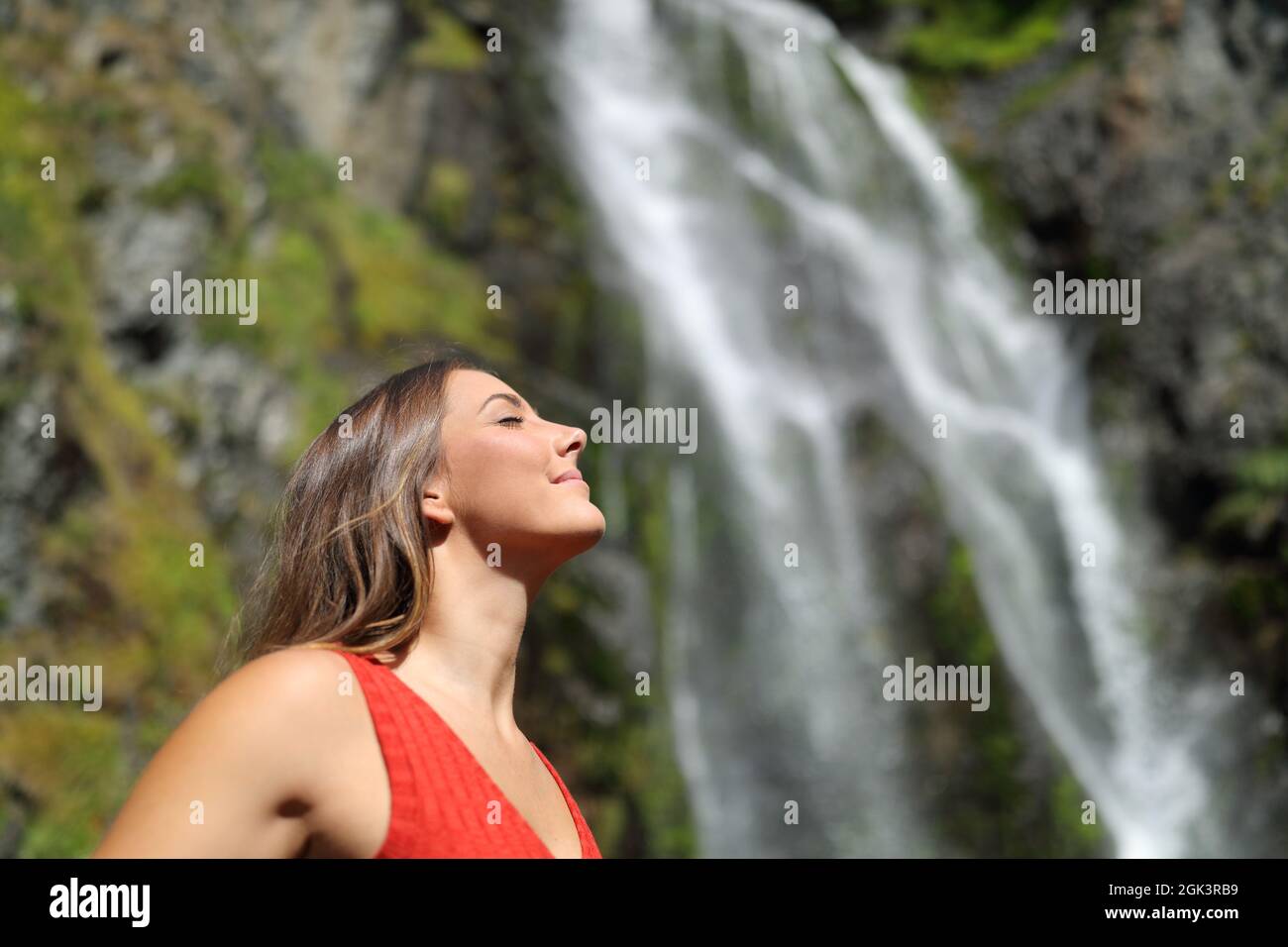Vue latérale d'une femme détendue respirant de l'air frais dans une chute d'eau Banque D'Images