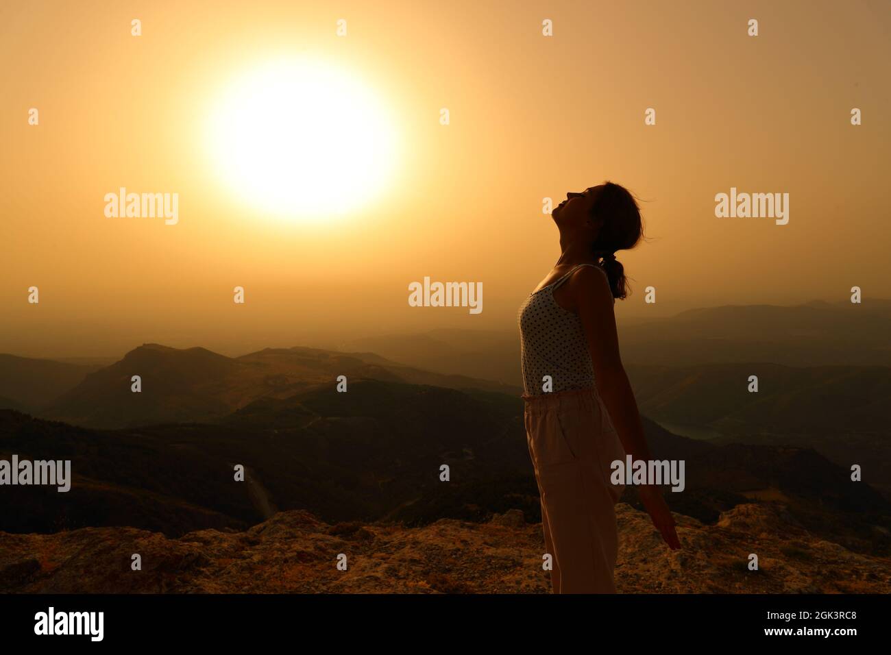 Profil d'une silhouette de femme respirant de l'air frais dans la montagne au coucher du soleil Banque D'Images