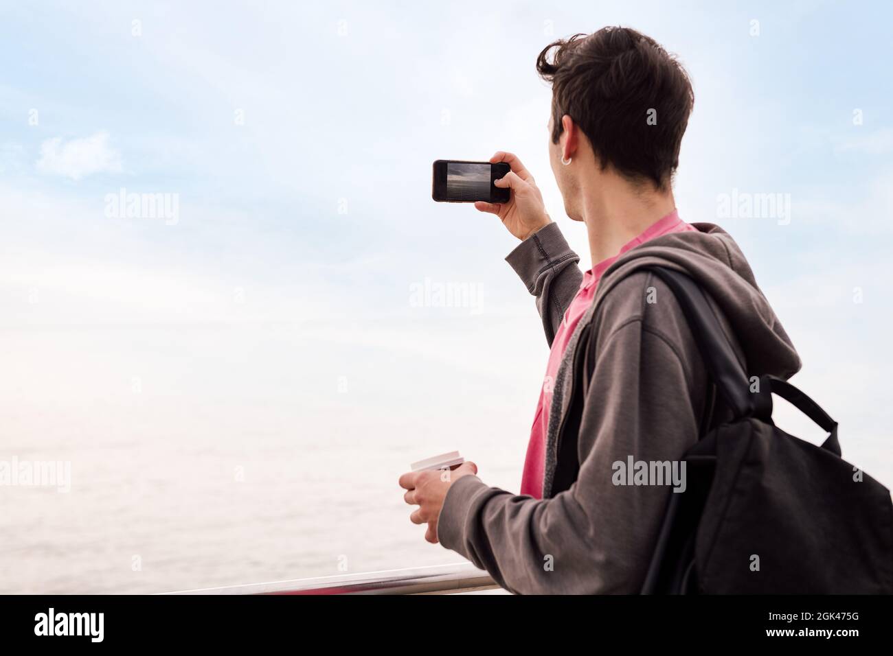 vue arrière d'un jeune homme avec sac à dos prendre une photo avec un téléphone mobile, concept de technologie et style de vie millénaire, espace de copie pour le texte Banque D'Images