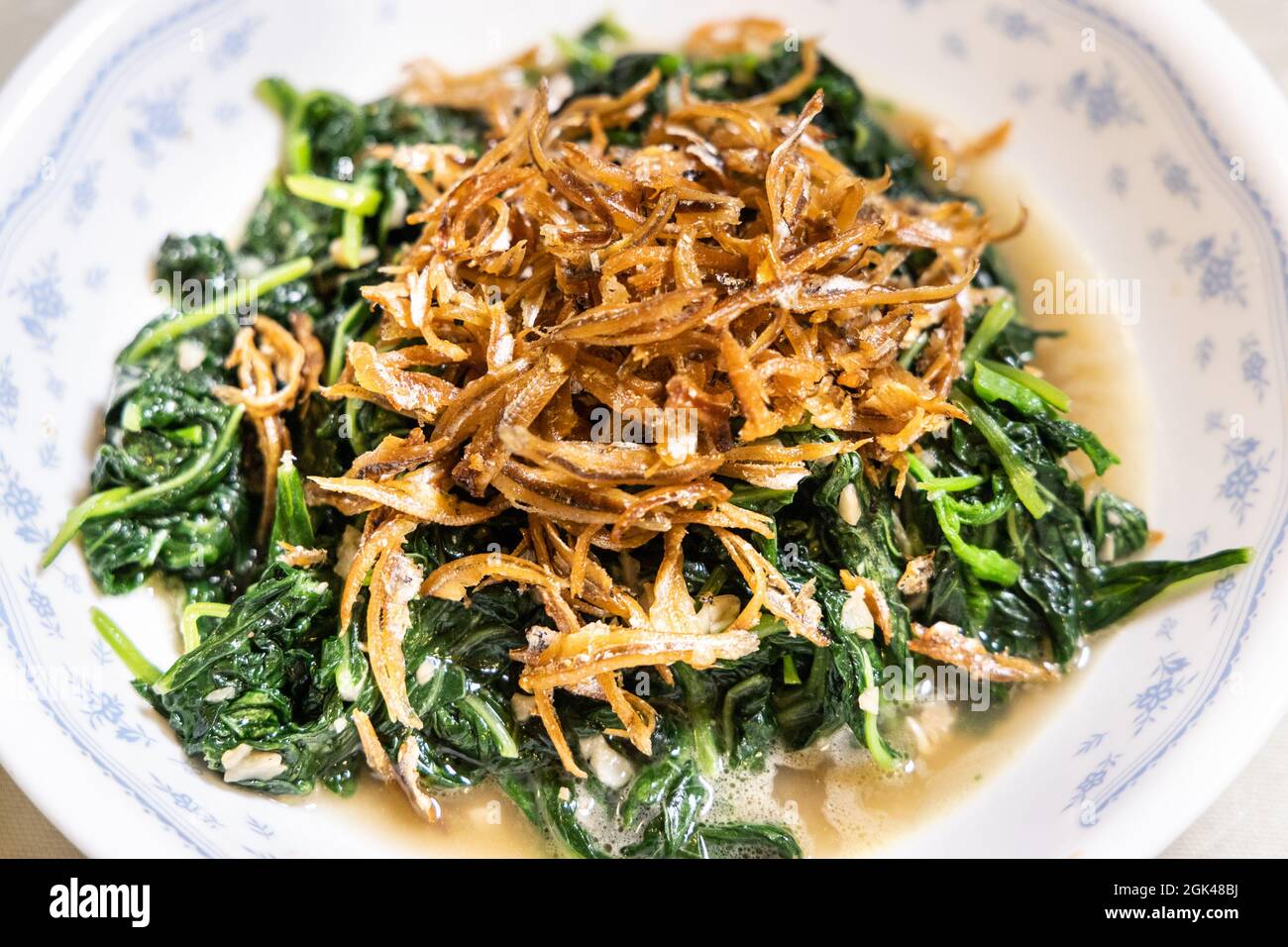 Gros plan sur un simple poêlage de légumes d'épinard vert d'amaranth chinois avec de l'ail, du sel et des anchois frits. Banque D'Images