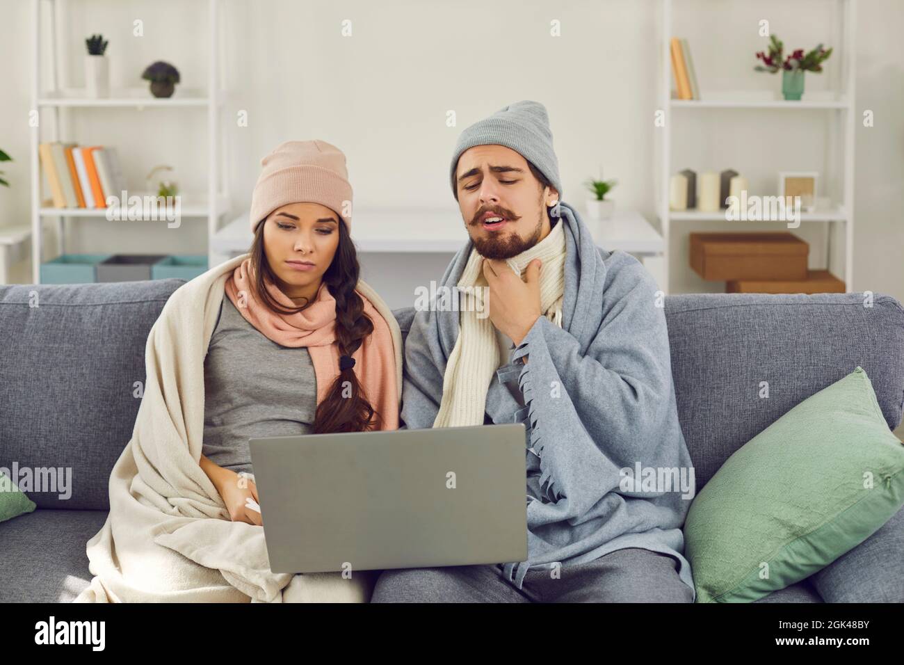 Couple, souffrant de la grippe, assis sur le canapé et ayant la consultation médicale par appel vidéo Banque D'Images