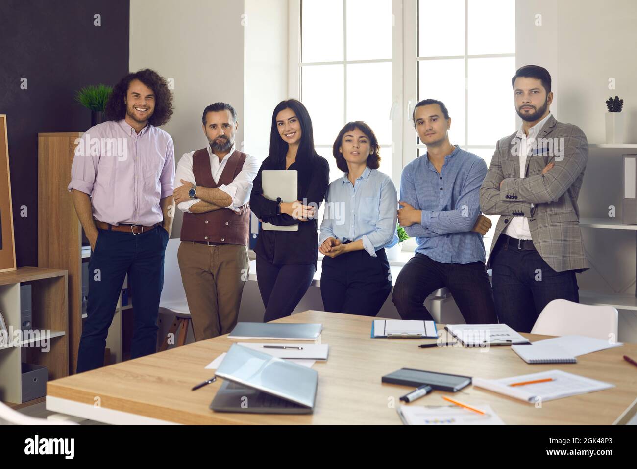 Une équipe de professionnels d'affaires heureux et réussis debout à côté de fenêtres dans un bureau moderne Banque D'Images