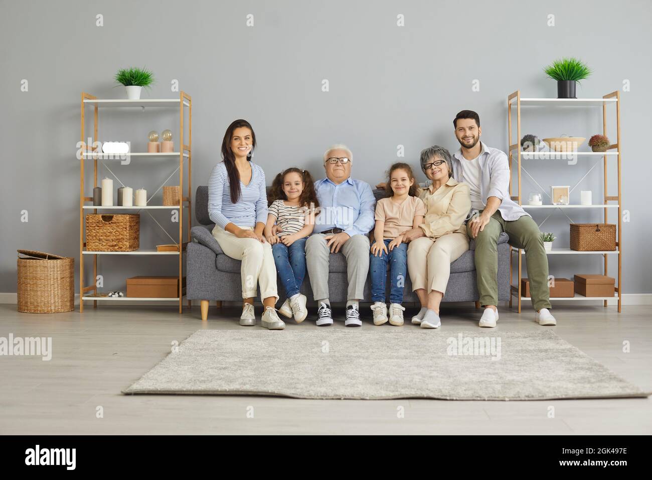 Portrait de trois générations d'une famille assise à la maison sur un canapé dans la salle de séjour. Banque D'Images