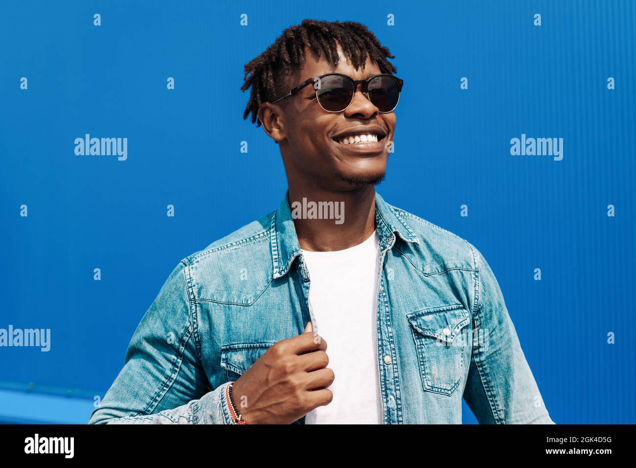 homme africain de mode en lunettes de soleil dans des vetements modernes et tendance posant sur le fond d un batiment bleu dans la rue Photo Stock Alamy