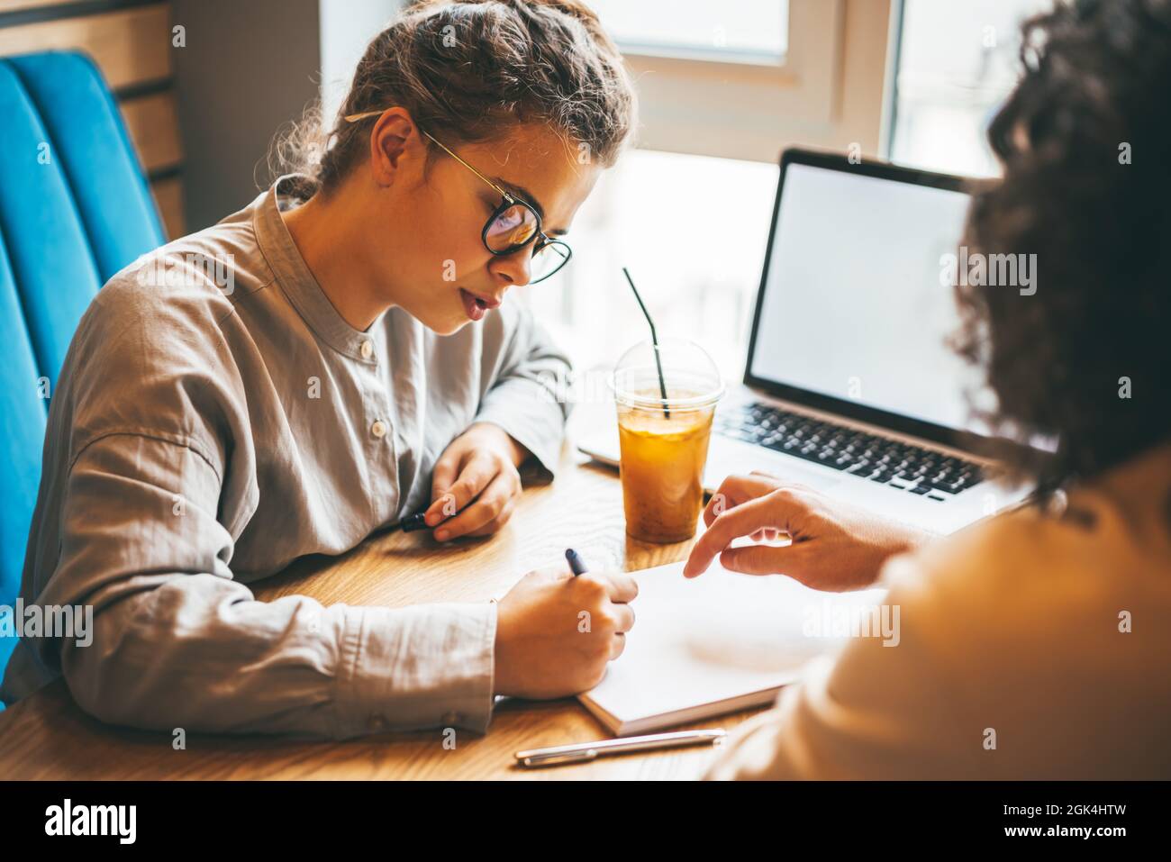 Jeune femme et homme caucasien travaillant et étudiant au café avec un ordinateur portable, discutant des tâches et se préparant à l'examen. Formation en ligne et cours sur Internet Banque D'Images
