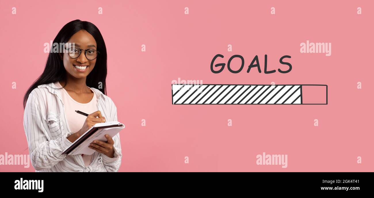 Smart Black femelle étudiant prenant des notes en copybook sur fond rose, collage avec DES OBJECTIFS de chargement de la barre de processus Banque D'Images