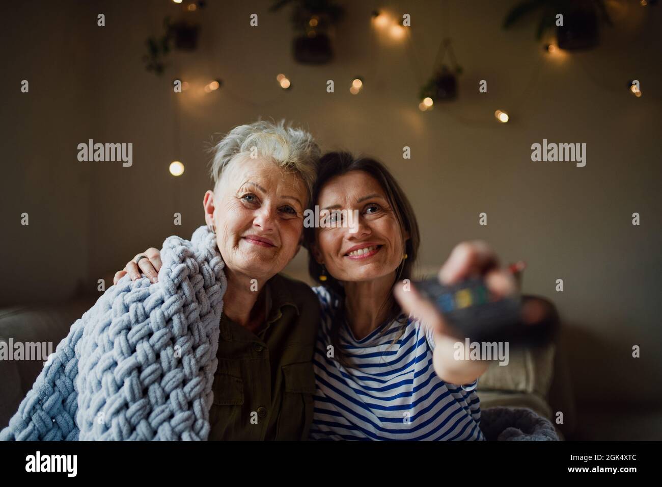 Portrait d'une mère âgée heureuse avec une fille adulte à l'intérieur à la maison, regardant la télévision. Banque D'Images