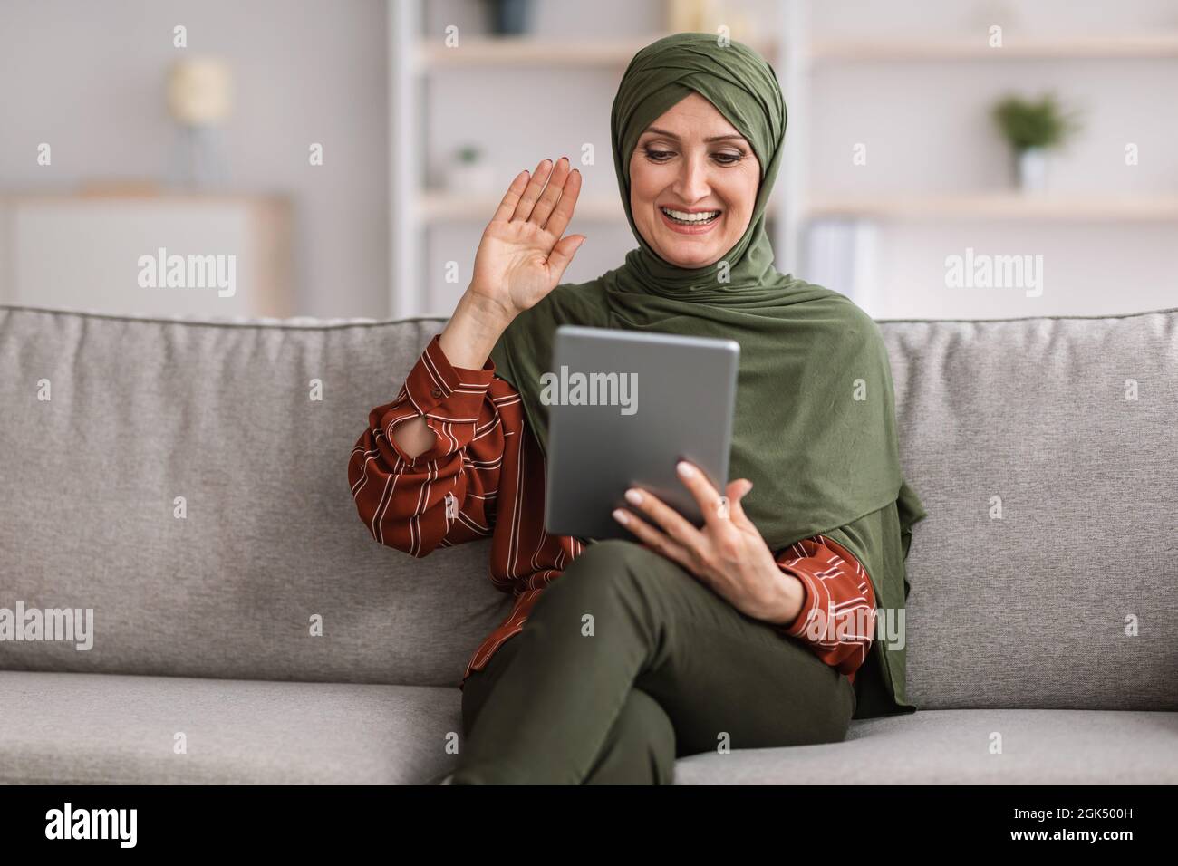 Bonne femme musulmane senior appels vidéo à l'aide d'une tablette à la maison Banque D'Images