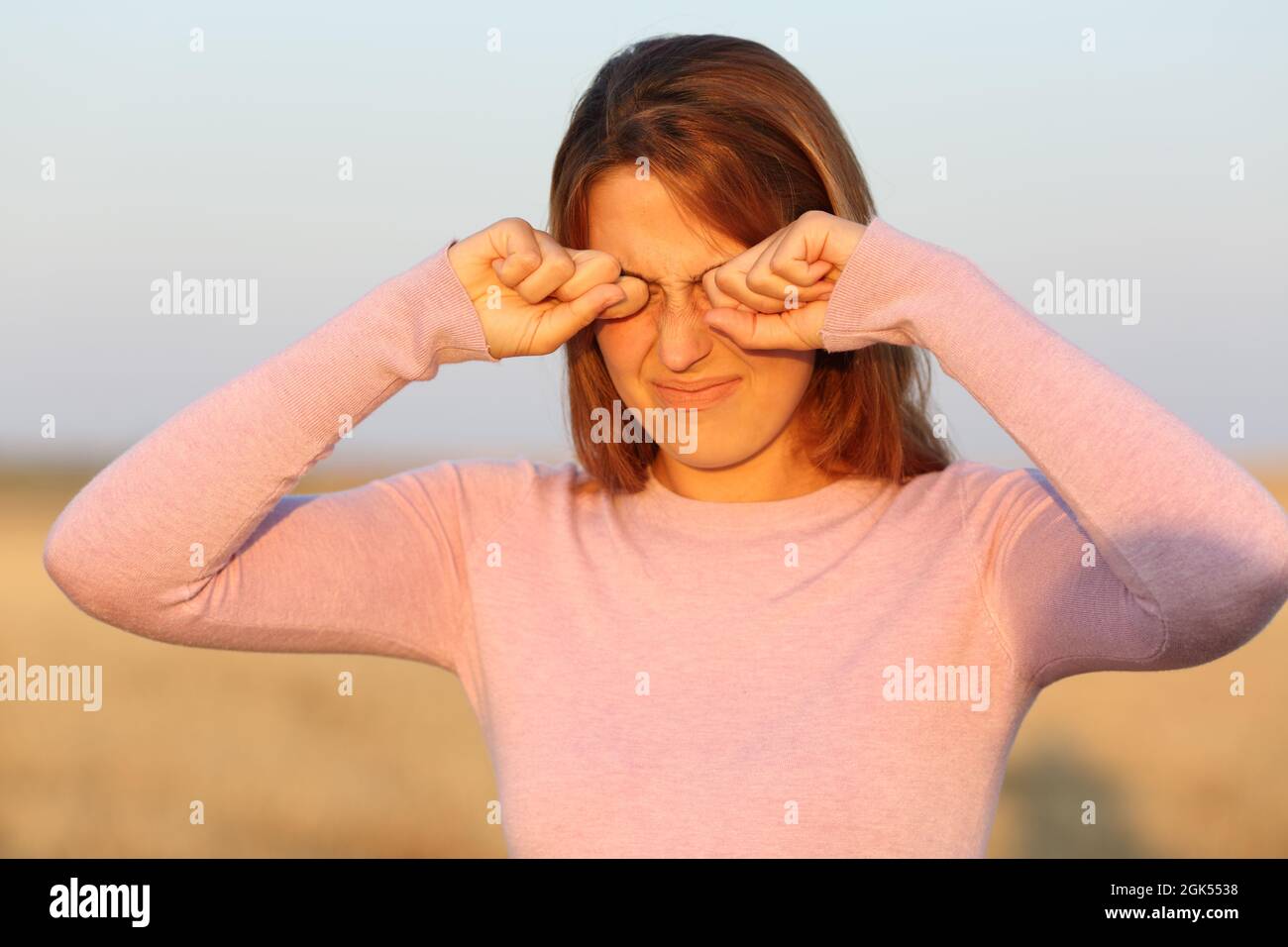 Femme se grattant les yeux en raison d'une allergie dans un champ de récolte Banque D'Images