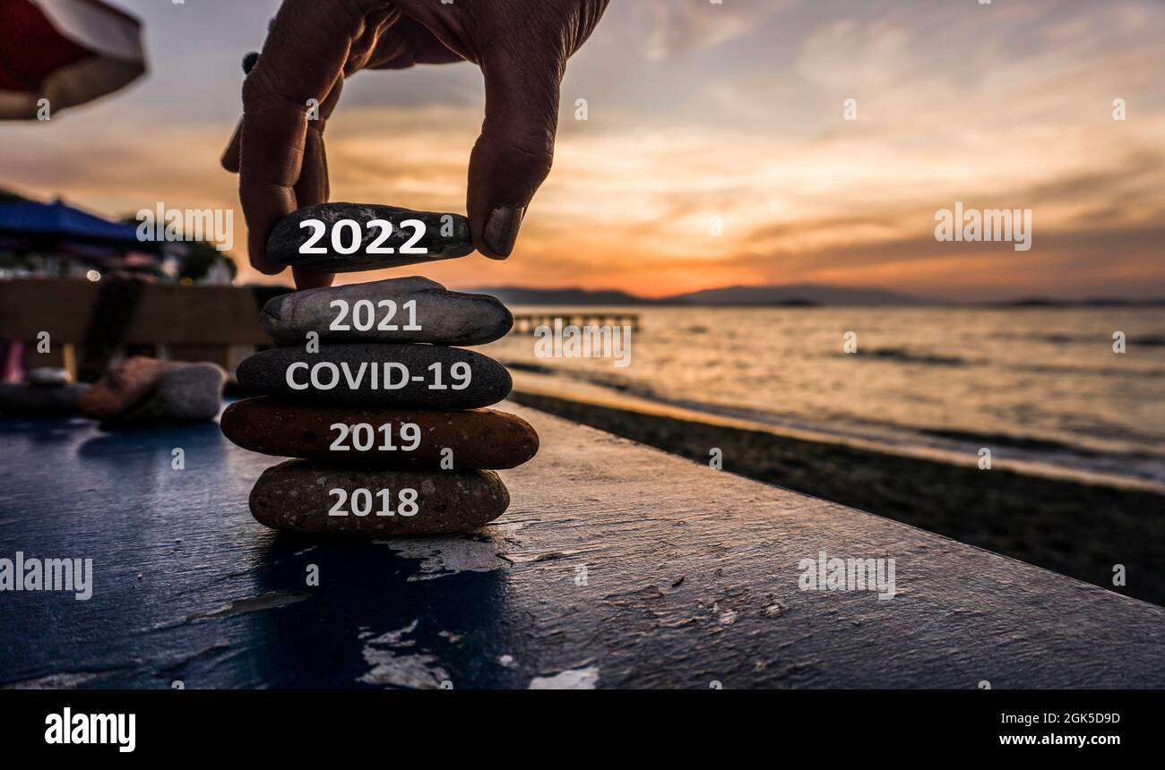 Le concept de la nouvelle année 2022 est à venir. L'ancienne année 2021 passe à 2022. Concept de bonne année. De nouveaux espoirs et de nouvelles excuses. Homme ajoutant de la pierre à la tour de galets. Banque D'Images
