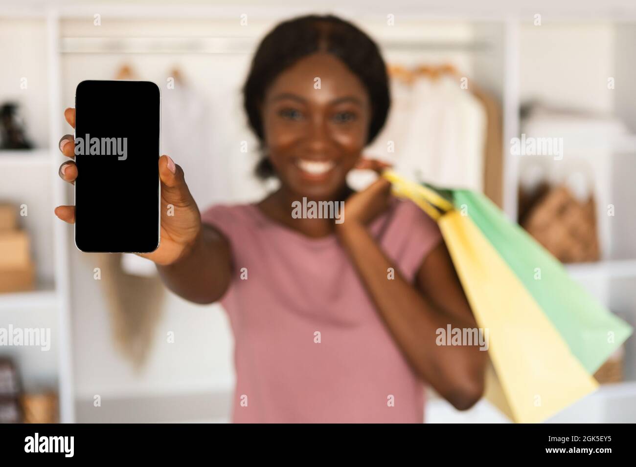 Femme noire montrant le téléphone écran vide de l'application publicitaire dans le magasin Banque D'Images
