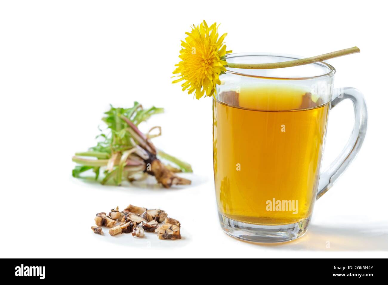 Thé pissenlit dans une tasse en verre avec fleur, feuilles et racine sur fond blanc. Banque D'Images