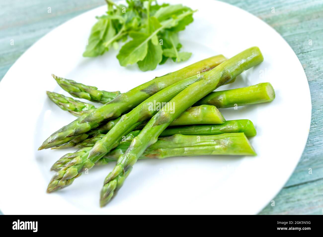 Gros plan des asperges cuites sur l'assiette sur une table en bois vert. Banque D'Images