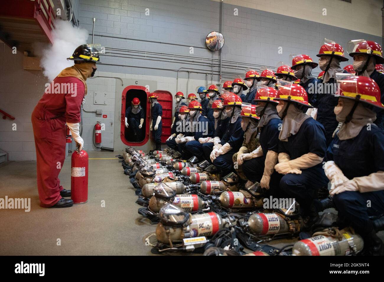 On montre aux recrues comment utiliser une bouteille de CO2 avant un exercice d'entraînement de lutte contre l'incendie à l'intérieur de l'entraîneur de pompiers en chef de l'USS au Commandement de l'entraînement de recrutement. Plus de 40,000 recrues s’entraînent chaque année dans le seul camp de la Marine. Banque D'Images