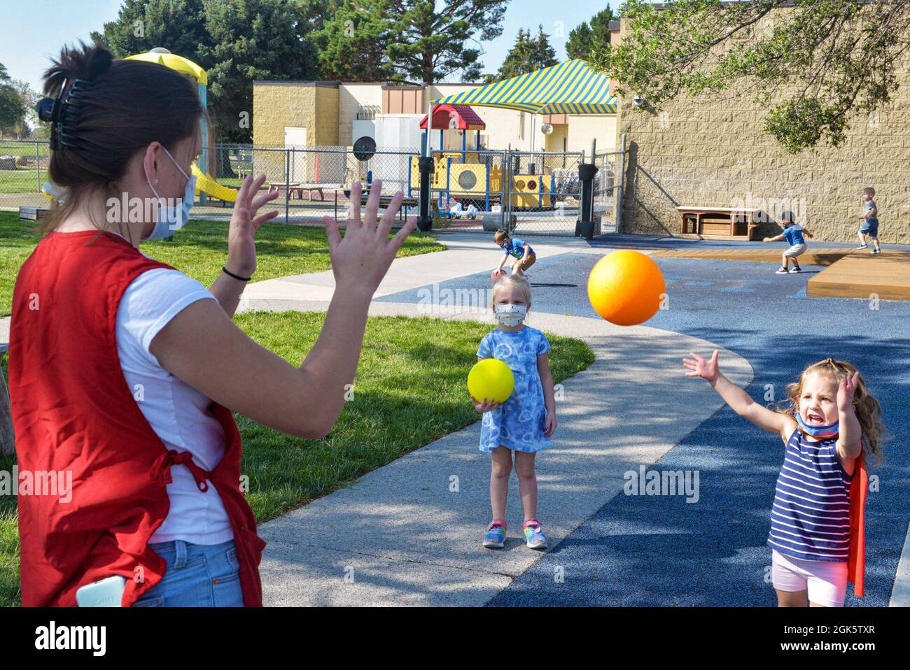 Alexis Pendergast, le personnel soignant du 366e Escadron de soutien de la Force, Centre de développement de l'enfant (CDC), lance une balle d'avant en arrière avec Olivia pendant le retrait de la base aérienne de Mountain Home, Idaho, le 10 août 2021. Le CDC offre aux enfants une participation active et pratique à leur environnement, à leurs pairs et à leurs adultes qui s'occupent de leur vie. Banque D'Images