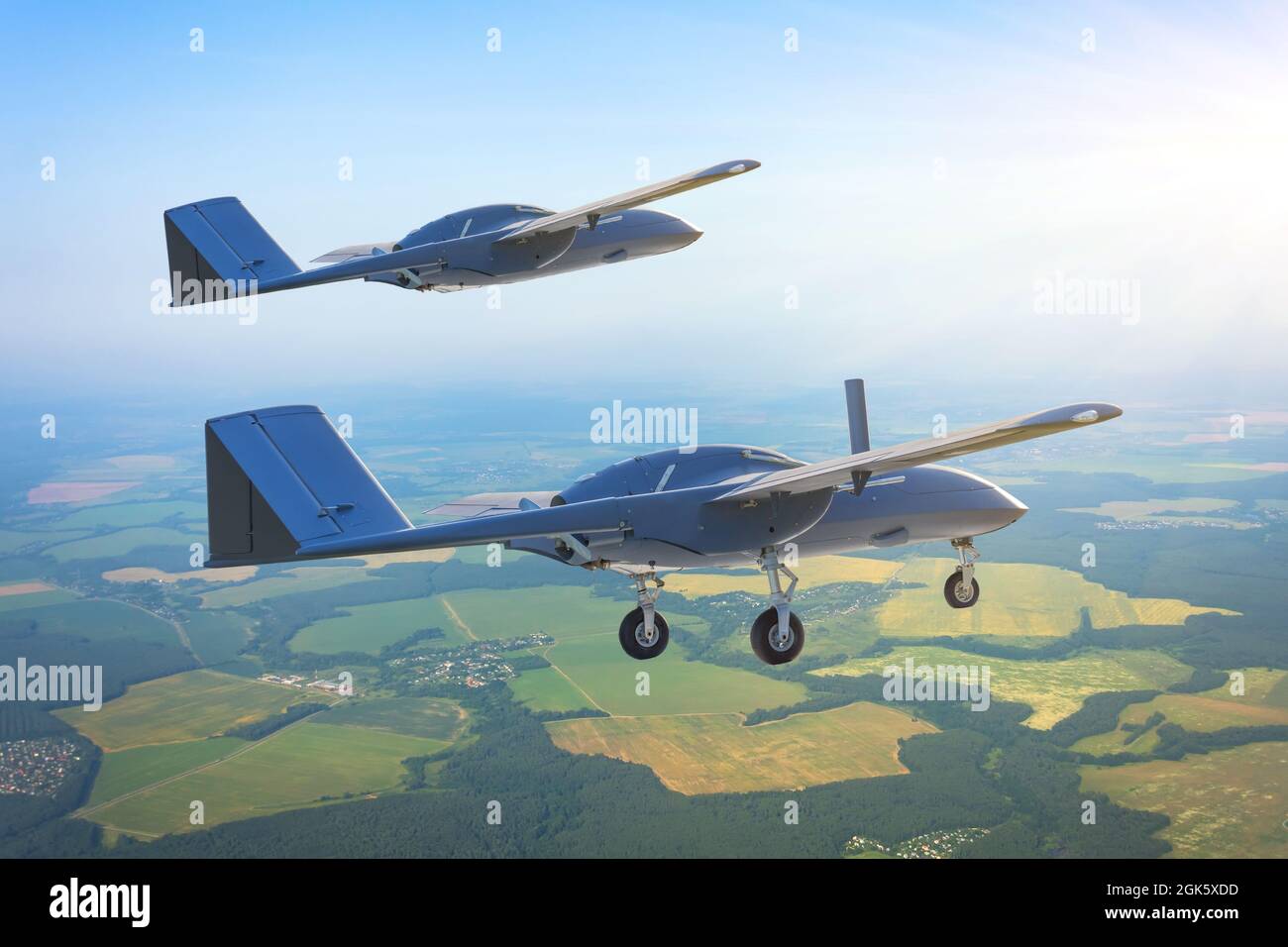 Une paire de drones militaires sans pilote avec des engins d'atterrissage étendus survole le territoire aérien de patrouille à basse altitude Banque D'Images