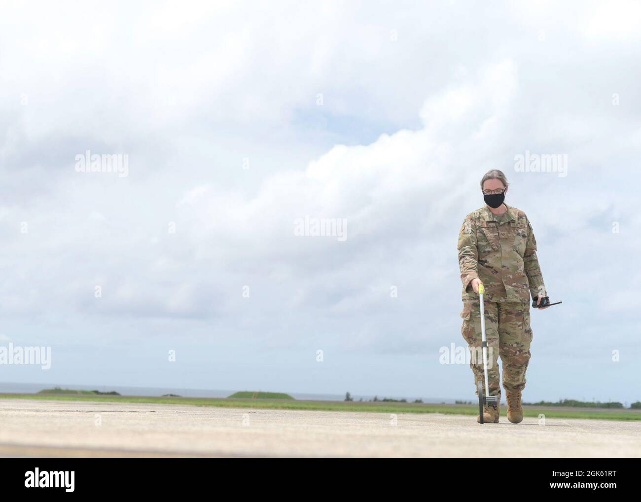 U.S. Air Force Tech. Sgt. Adrienne Fields, du 18e Escadron de soutien aux opérations, NCO, en charge des opérations de gestion des terrains d'aviation, démontre l'utilisation d'une roue de mesure à la base aérienne de Kadena, au Japon, le 11 août 2021. Un des éléments de la sécurité de la piste pour les pilotes et les avions consiste à inspecter les marquages sur l'aérodrome pour s'assurer qu'ils ont été peints avec précision et dans les limites de la réglementation. Banque D'Images