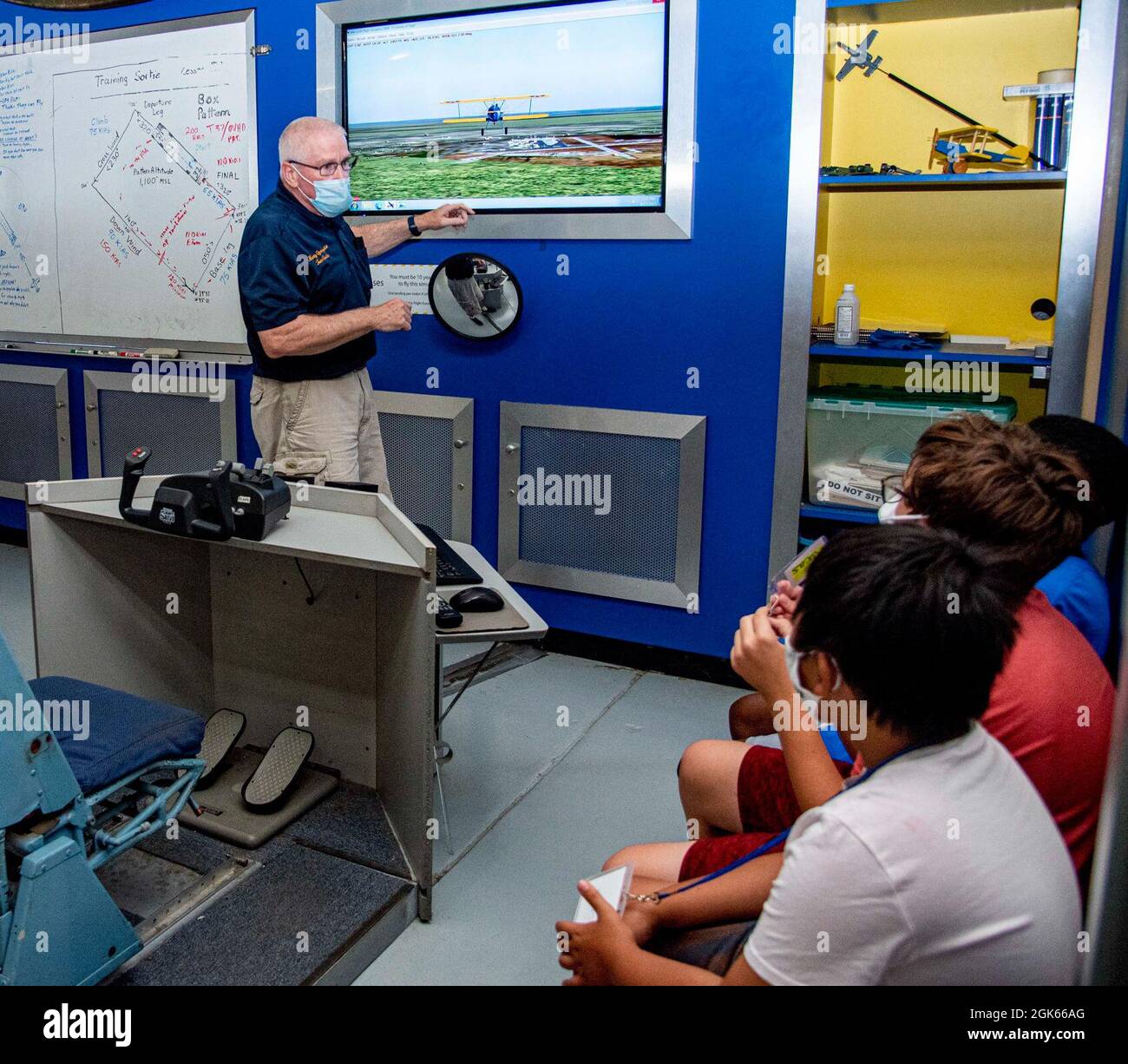 John Martin, bénévole du Air Mobility Command Museum, explique aux participants du camp d'aviation d'été comment le simulateur de vol fonctionne au Musée AMC, sur la base aérienne de Douvres, Delaware, le 10 août 2021. Les participants ont eu l'occasion de voler un avion Staarman simulé, de voler dans un Cessna avec le Dover AFB Aero Club, d'interroger des aviateurs et des retraités et d'en apprendre plus sur l'armée. Le camp d’été de cette année a utilisé des salles de classe Quonset Hut créées au cours de la pandémie de l’an dernier et peut également être utilisé par des parents à domicile. Banque D'Images