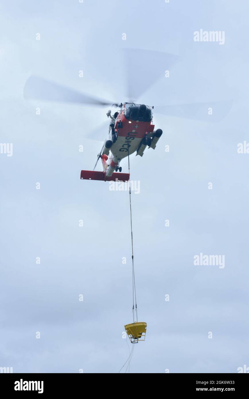 La photo montre un hélicoptère MH-60 Jayhawk, de la U.S. Coast Guard Sector Columbia River, qui hante un conteneur rempli de béton tout en menant une formation de mise en eau de béton avec des aides à la navigation Team Astoria, le mercredi 18 août 2021, à Astoria, Oregon. Les deux équipes ont mené la formation sur le béton pour se préparer à un projet de reconstruction à venir, où elles pourront servir de base pour de nouvelles aides à la navigation. Banque D'Images