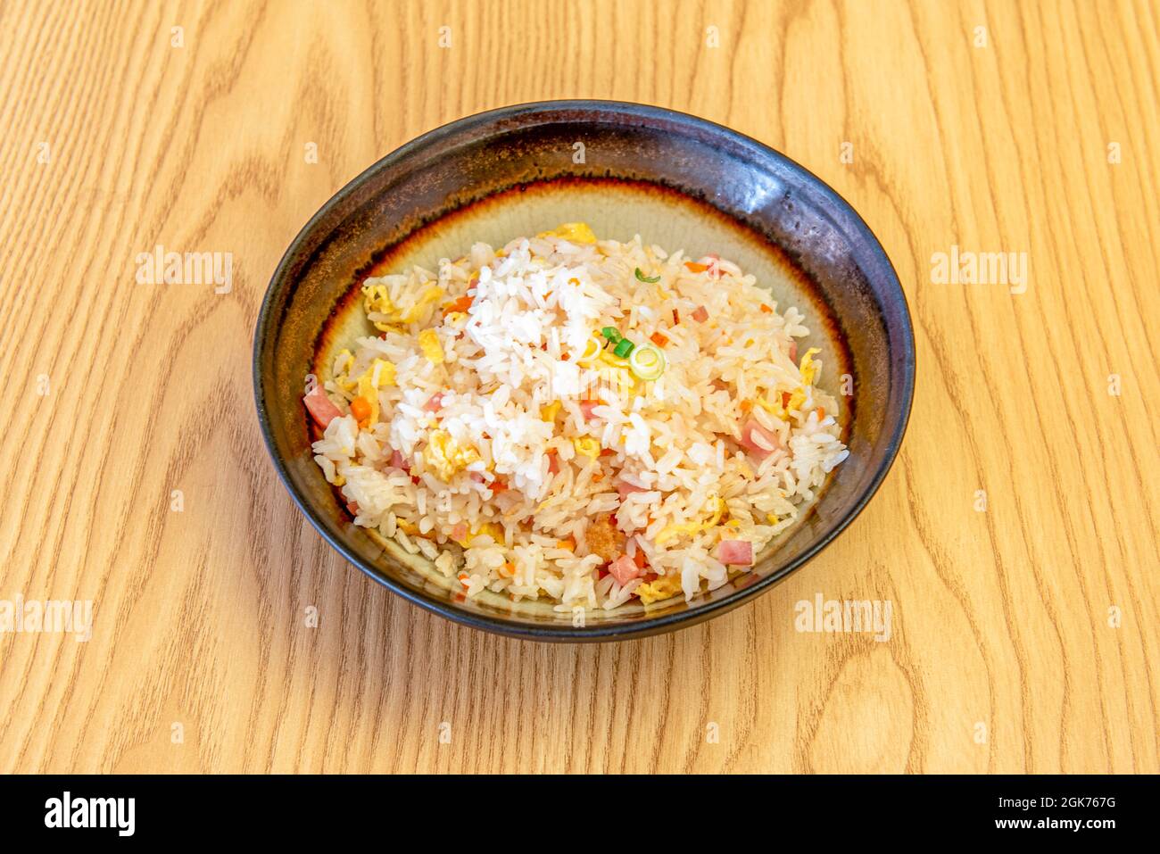 Riz aux légumes, au jambon, à la ciboulette, aux carottes et aux omelettes sautées au restaurant chinois dans un bol sombre Banque D'Images