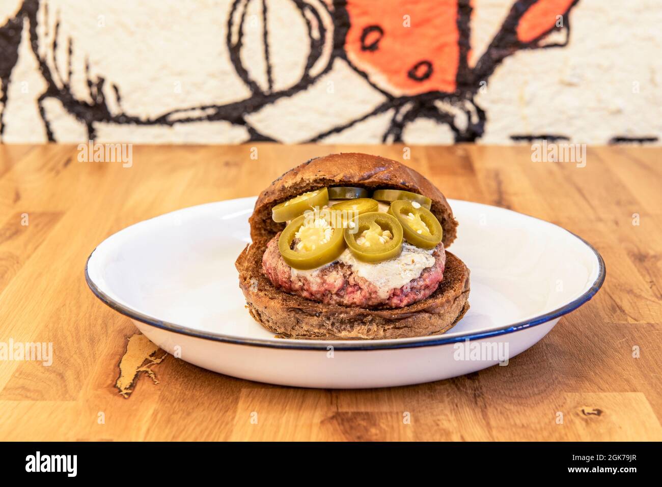 hamburger de bœuf avec pain de seigle, fromage bleu fondu et tranches de jalapeño sur une assiette blanche Banque D'Images hamburger de bœuf avec pain de seigle, fromage bleu fondu et tranches de jalapeño sur une assiette blanche Banque D'Images
