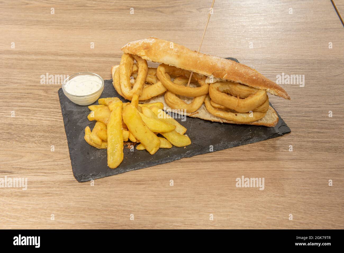 Sandwich de rondelles de calmar battues avec de la farine et des œufs, sauce mayonnaise et côté de frites Banque D'Images